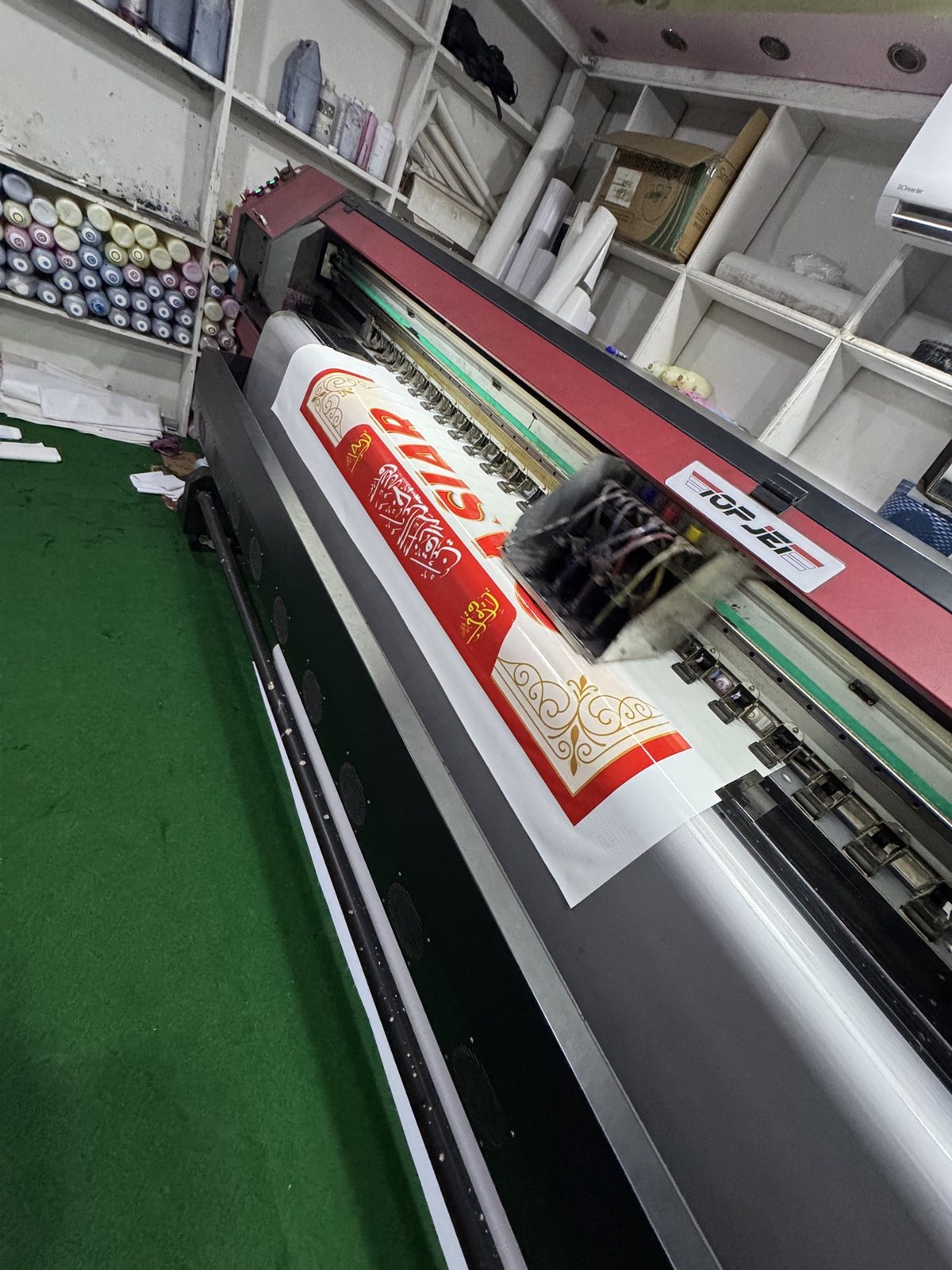 PRINT POINT's own large format printer in the shop, printing a red flex banner